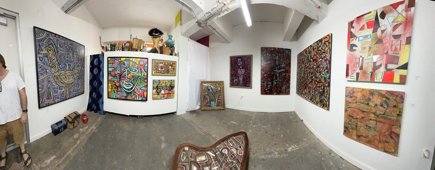 Panorama of Karl Lubbering's studio walls hung with paintings.